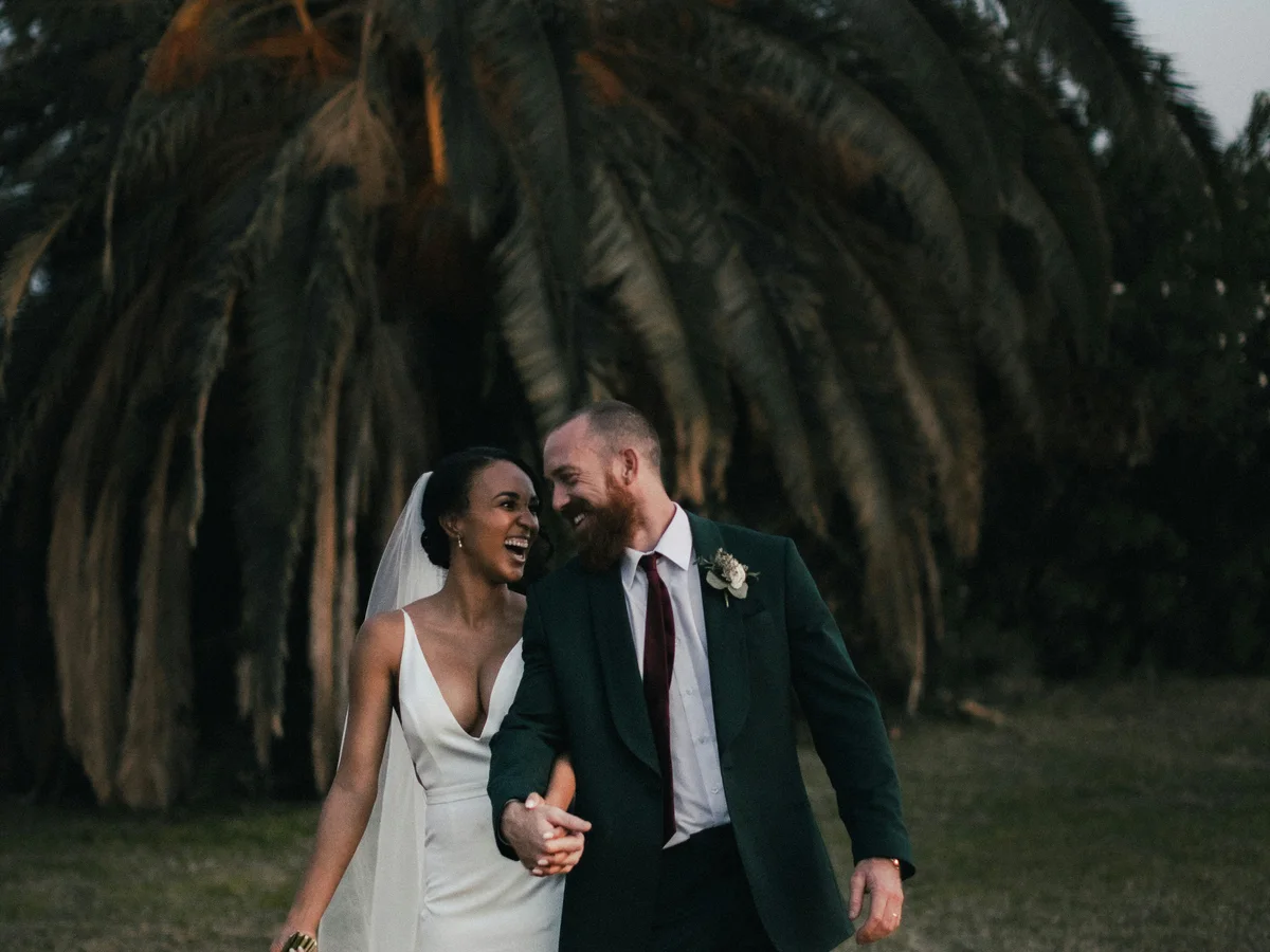 Illustrative wedding portrait of a couple walking beneath palm trees